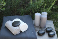 Arrangement Hot-Stone Massage mit Handt&uuml;chern, Kerezen und Hot-Stones